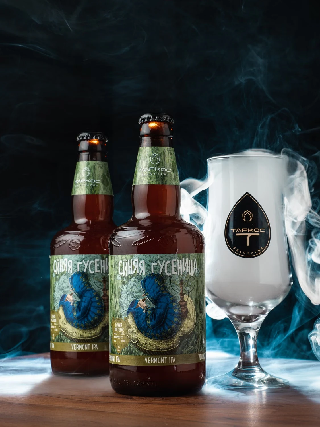 Craft IPA bottles with illustrated labels and a tasting glass against a dark smoky backdrop