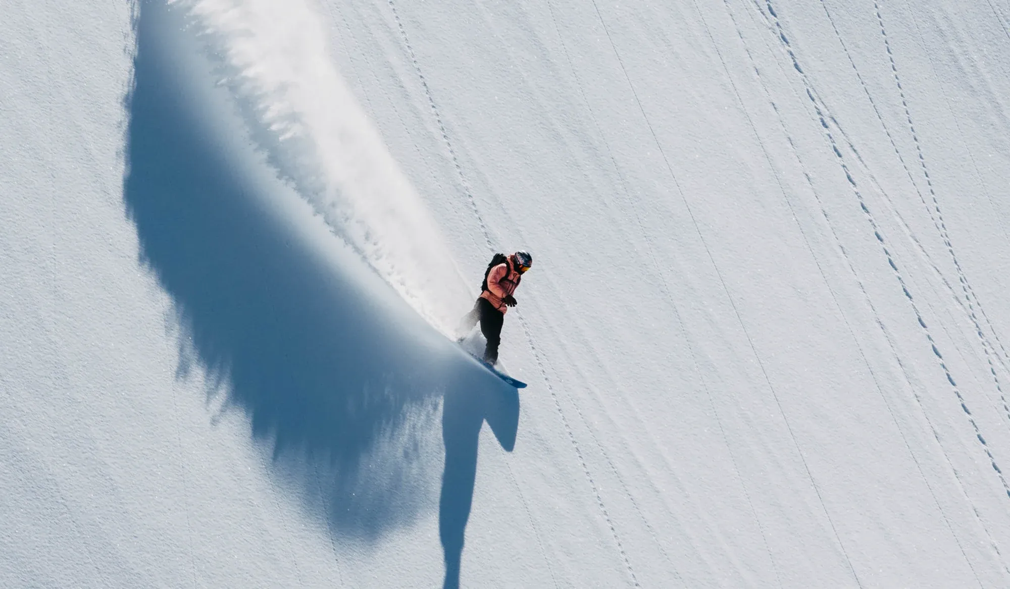 12 Boards snowboarder carving a turn through deep mountain snow